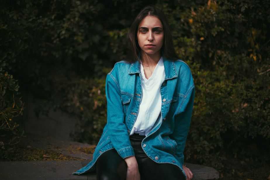 girl in a blue shirt with white t-shirt sitting in a rock looking stoic