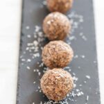 Peanut butter balls on a slate with coconut shavings