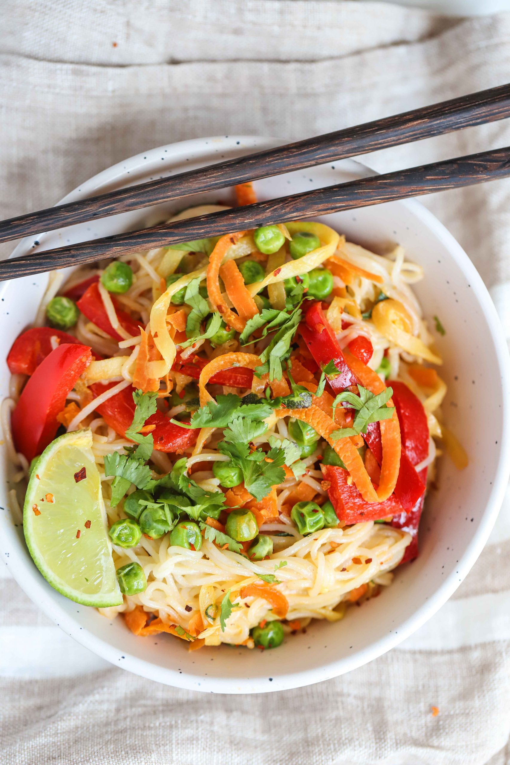 Vegetable stir-fry in a white bowl with chop sticks on the side