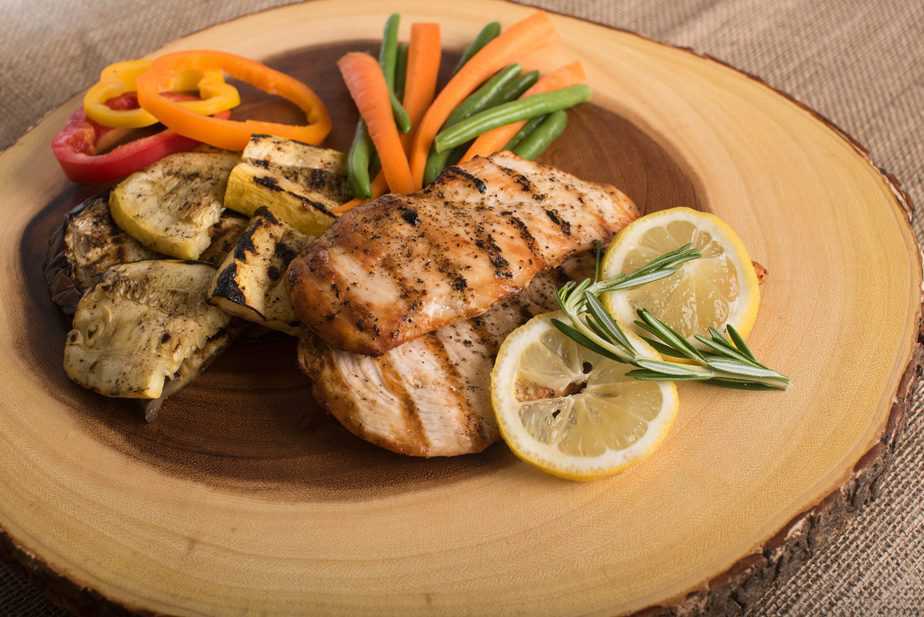 Chicken on a wood cutting board with veggies