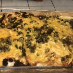 A glass dish with a layer of tortillas covered in cheese and black beans