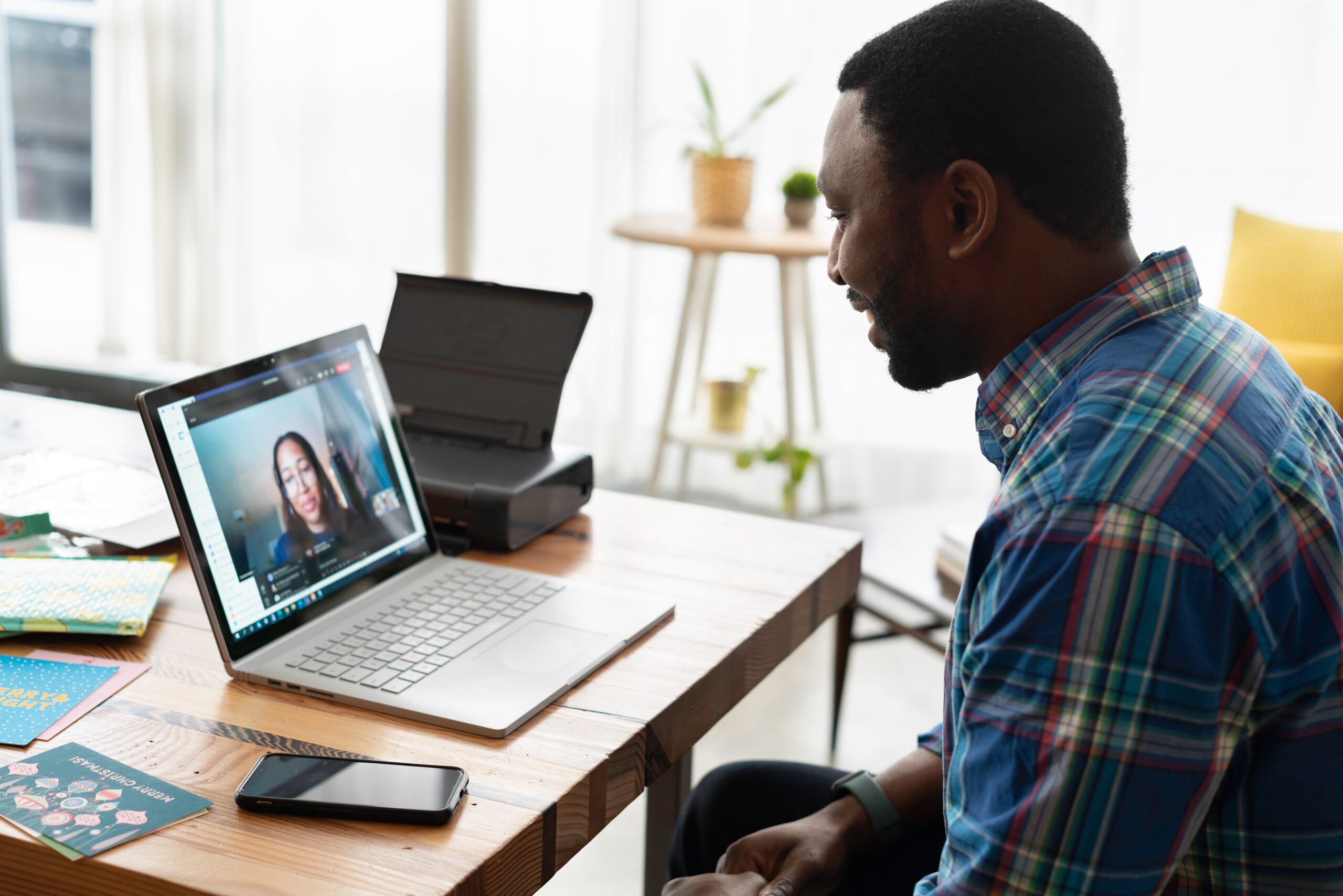 Man looking at a computer screen with a woman on it. Online coaching.