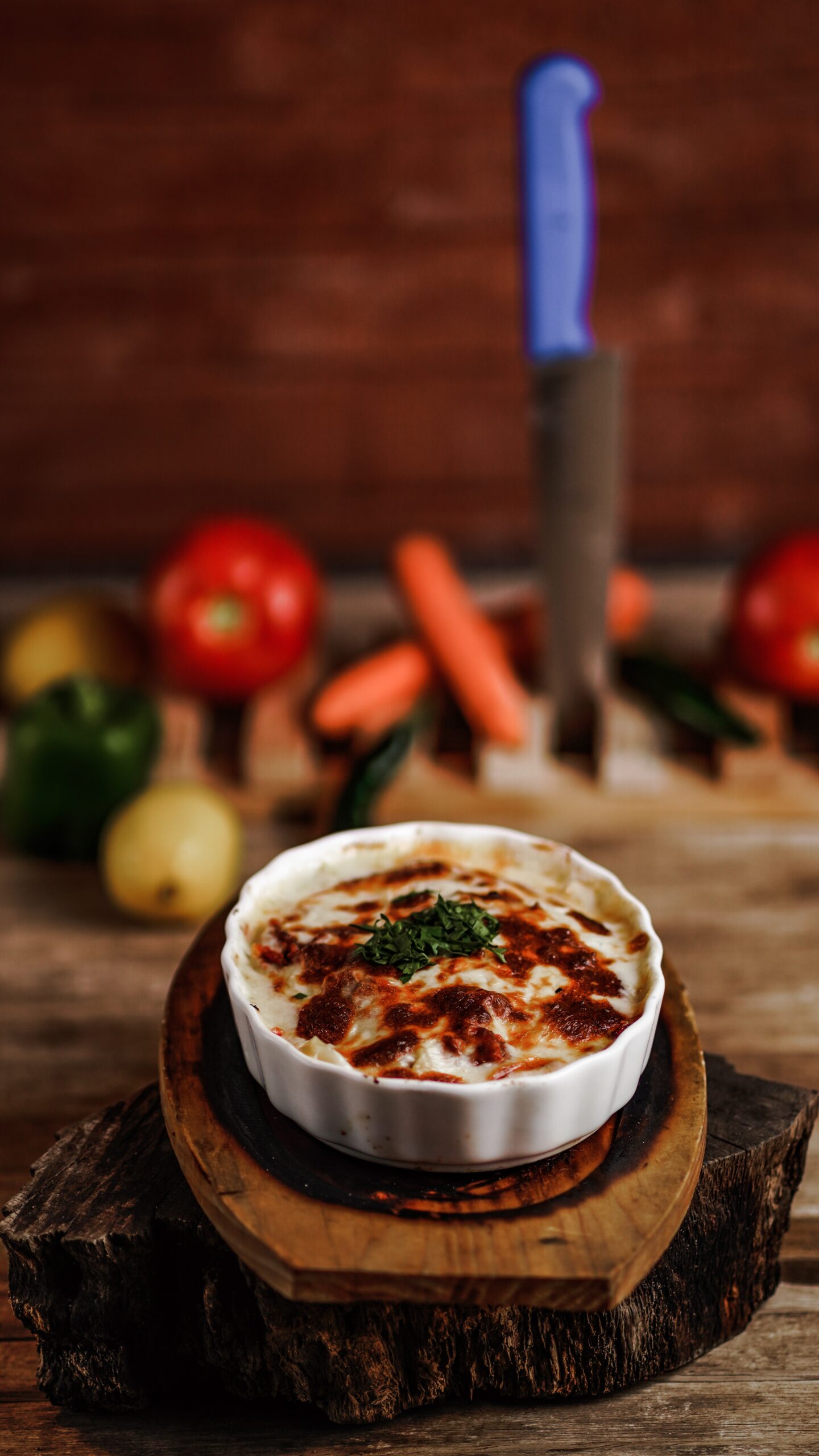 lasagna in a white bowl on a round wood cutting board