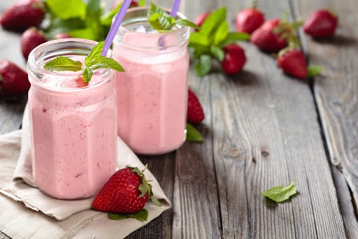 Fruit smoothie with mint leaves on wooden rustic table.